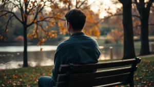 A person dealing with grief sits in a park, surrounded by nature's beauty, reflecting on loss.